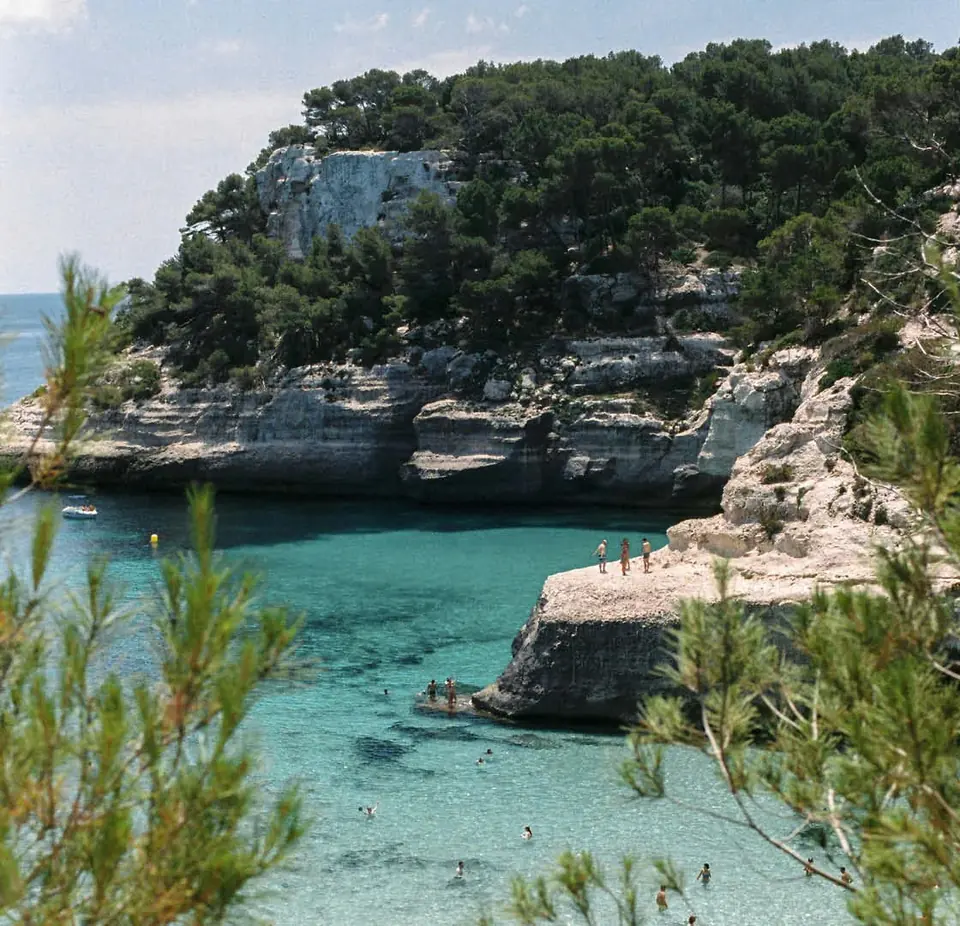 Bucht mit türkisfarbenem Wasser zwischen Klippen und Pinienwäldern